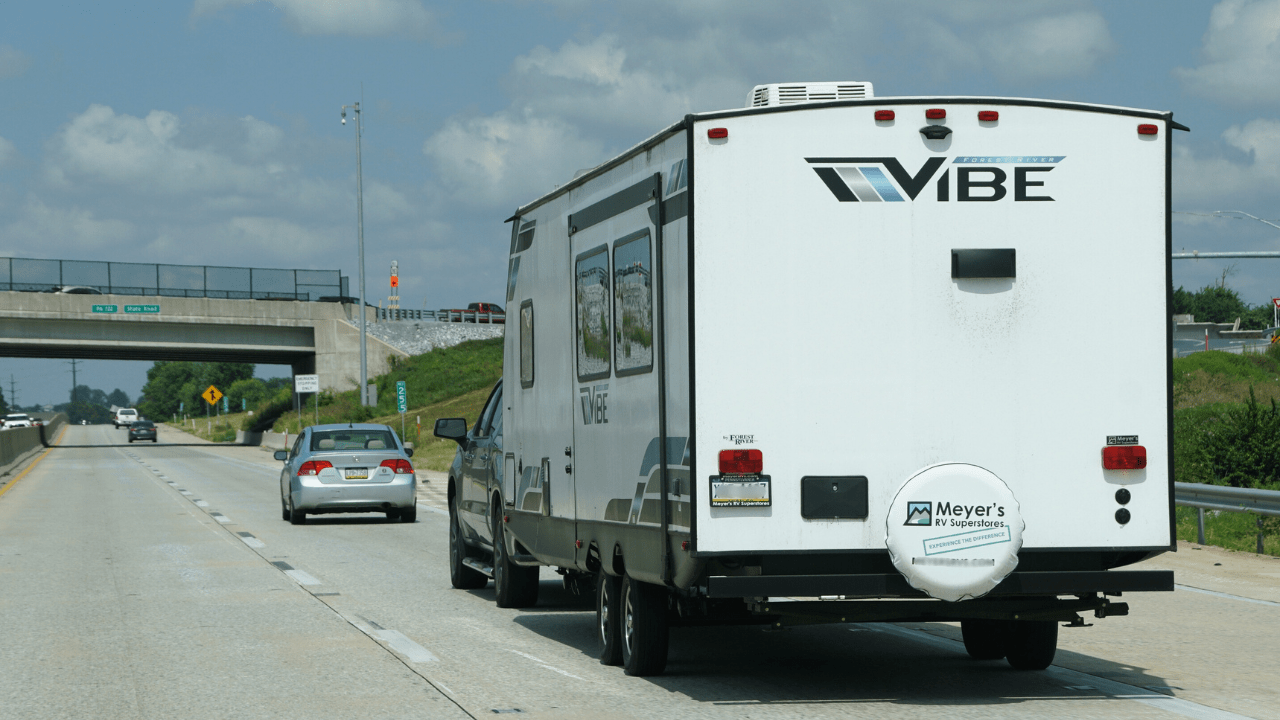 A white Forest River Vibe RV travels down the highway