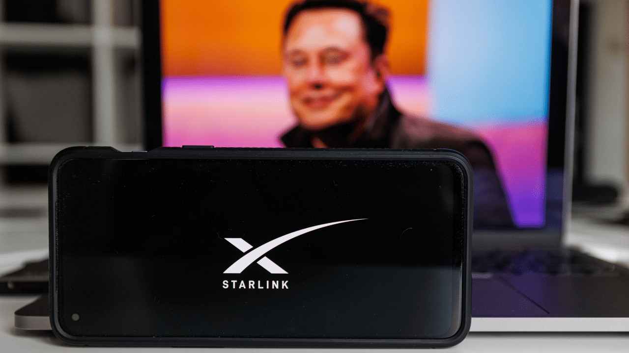 Starlink logo on screen and Elon Musk in background