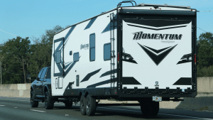 A black and white Momentum Grand Design travel trailer towed by pickup truck