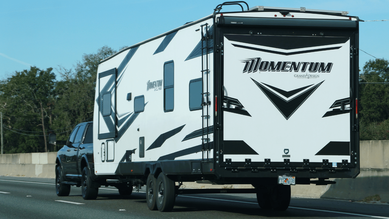 A black and white Momentum Grand Design travel trailer towed by pickup truck