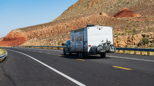 A truck pulling a travel trailer along a mountain road in the Mojave Desert