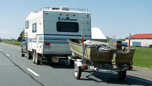 Coachman traveling camper towing fishing boat on the highway