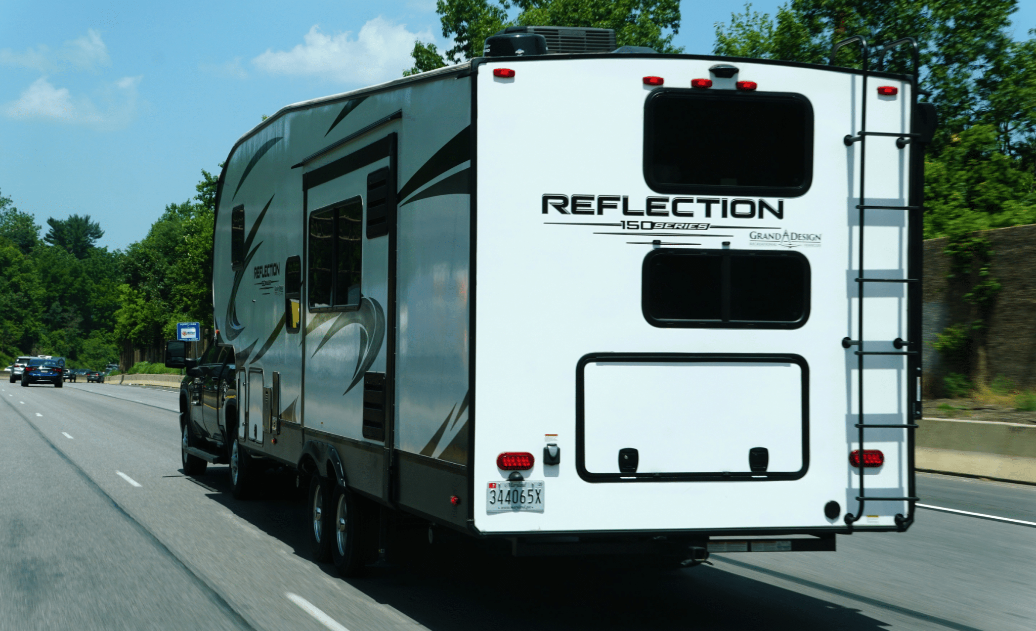Reflection 150 Series fifth-wheel trailer towed by a pickup truck on the highway